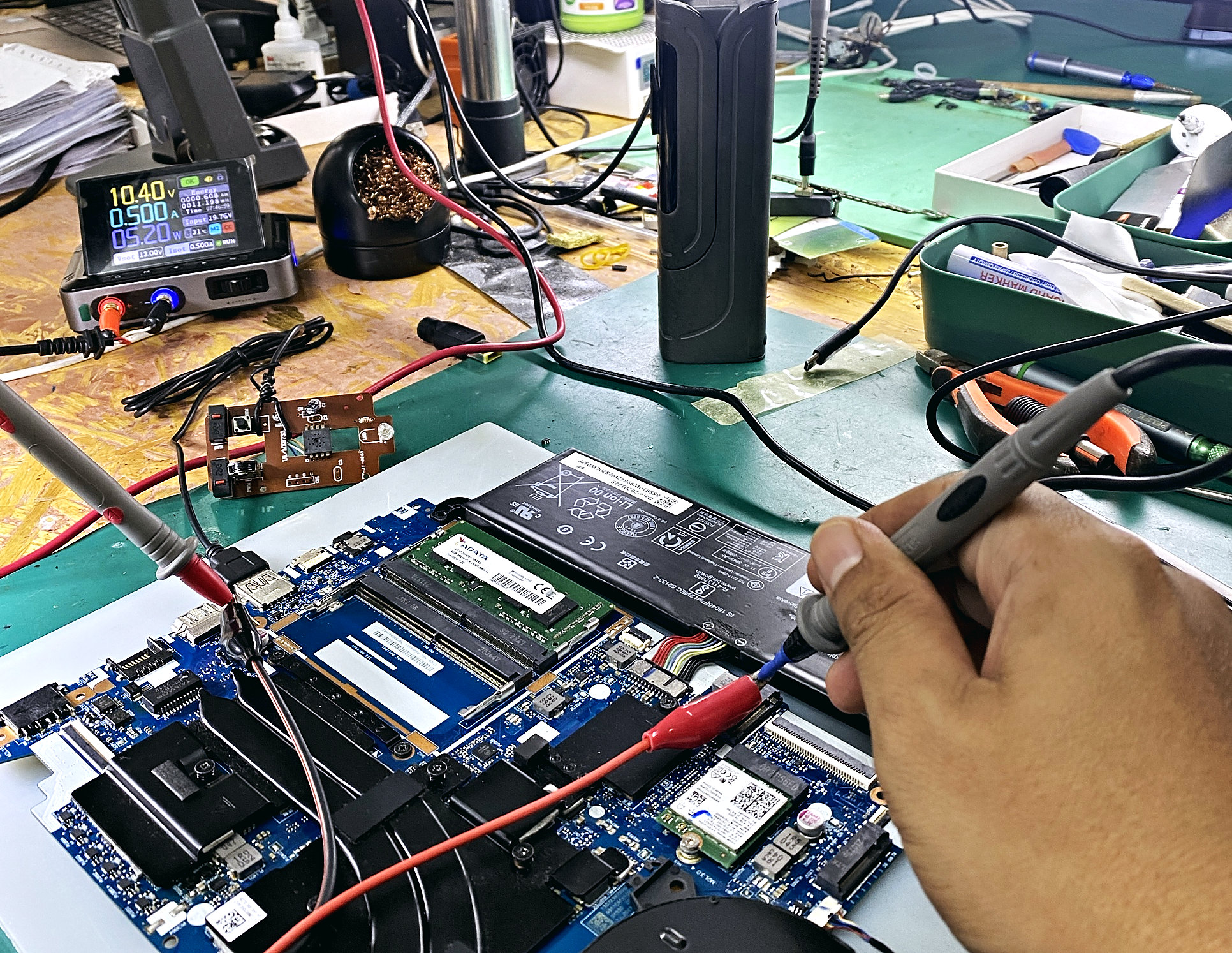 Teknisian 4VOLTS mengukur voltan pada motherboard laptop